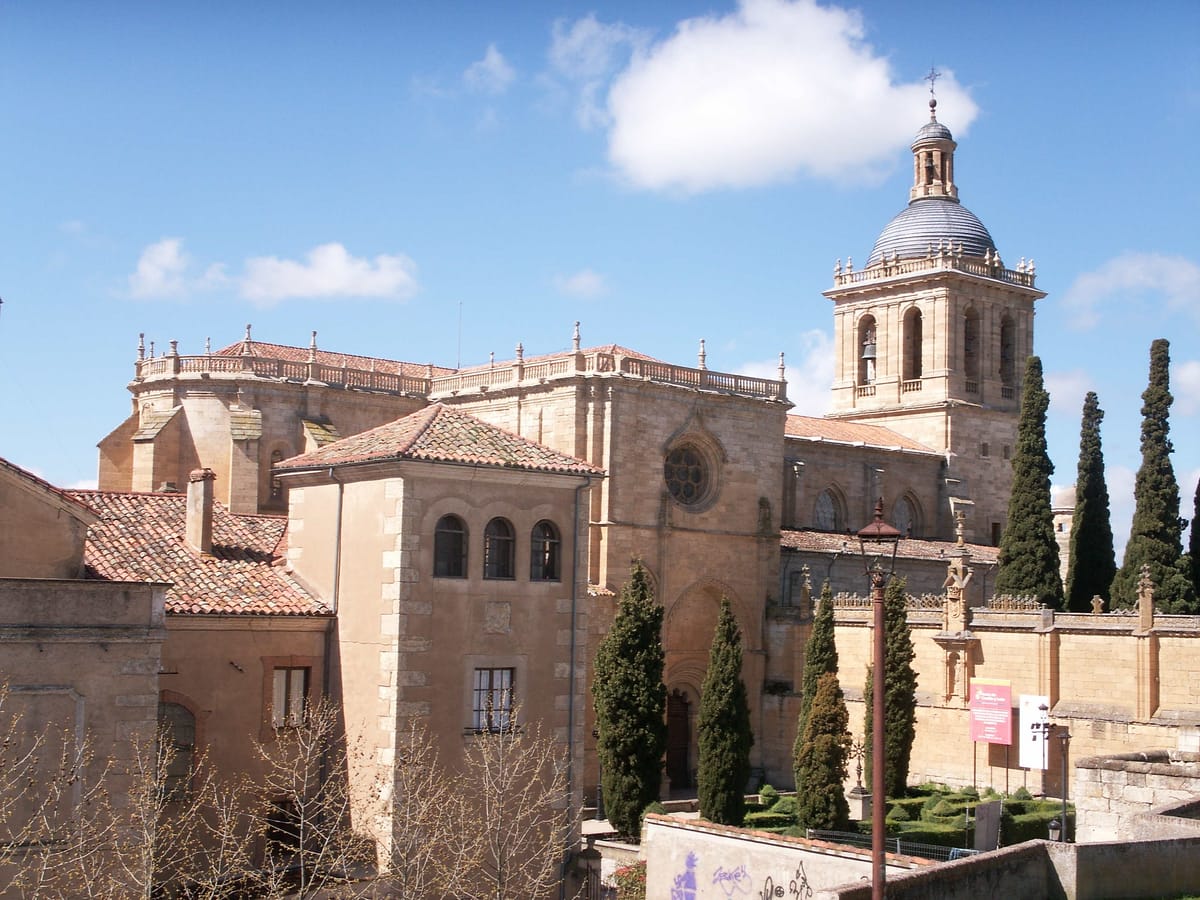 A catedral de Ciudad Rodrigo vista de lado, com a torre de cúpula e ciprestes à frente
