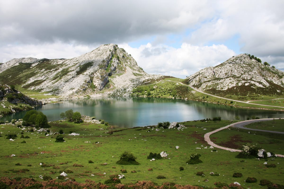 Lago de montanha cercado de prados verdes e picos de calcário
