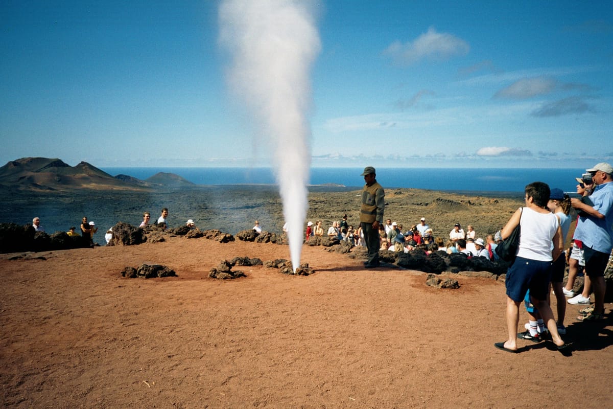 Água derramada num buraco do solo volta como jato de vapor, uma das demonstrações de calor subterrâneo em Timanfaya