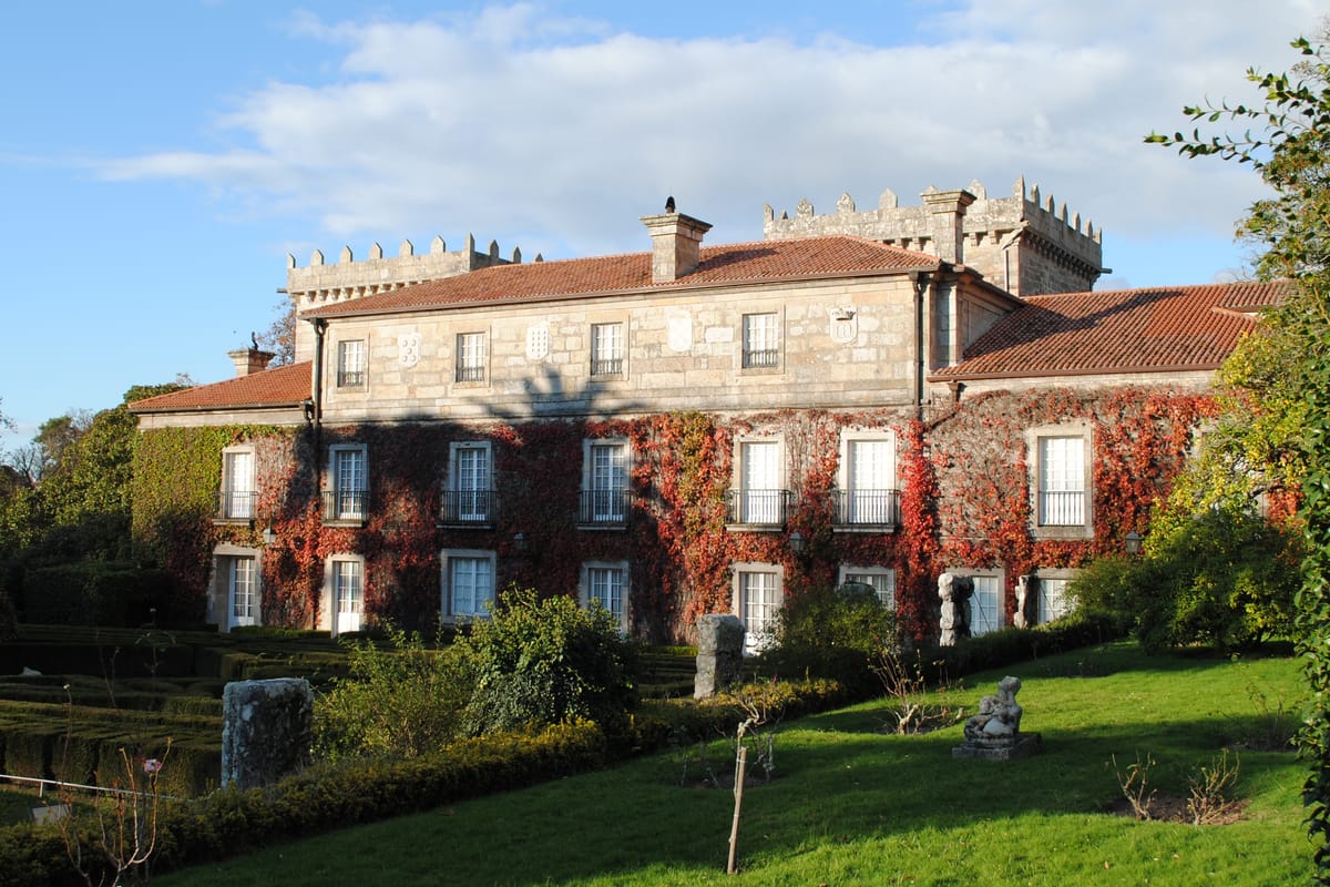 Fachada de pedra do pazo de Castrelos, com torres e jardim em frente