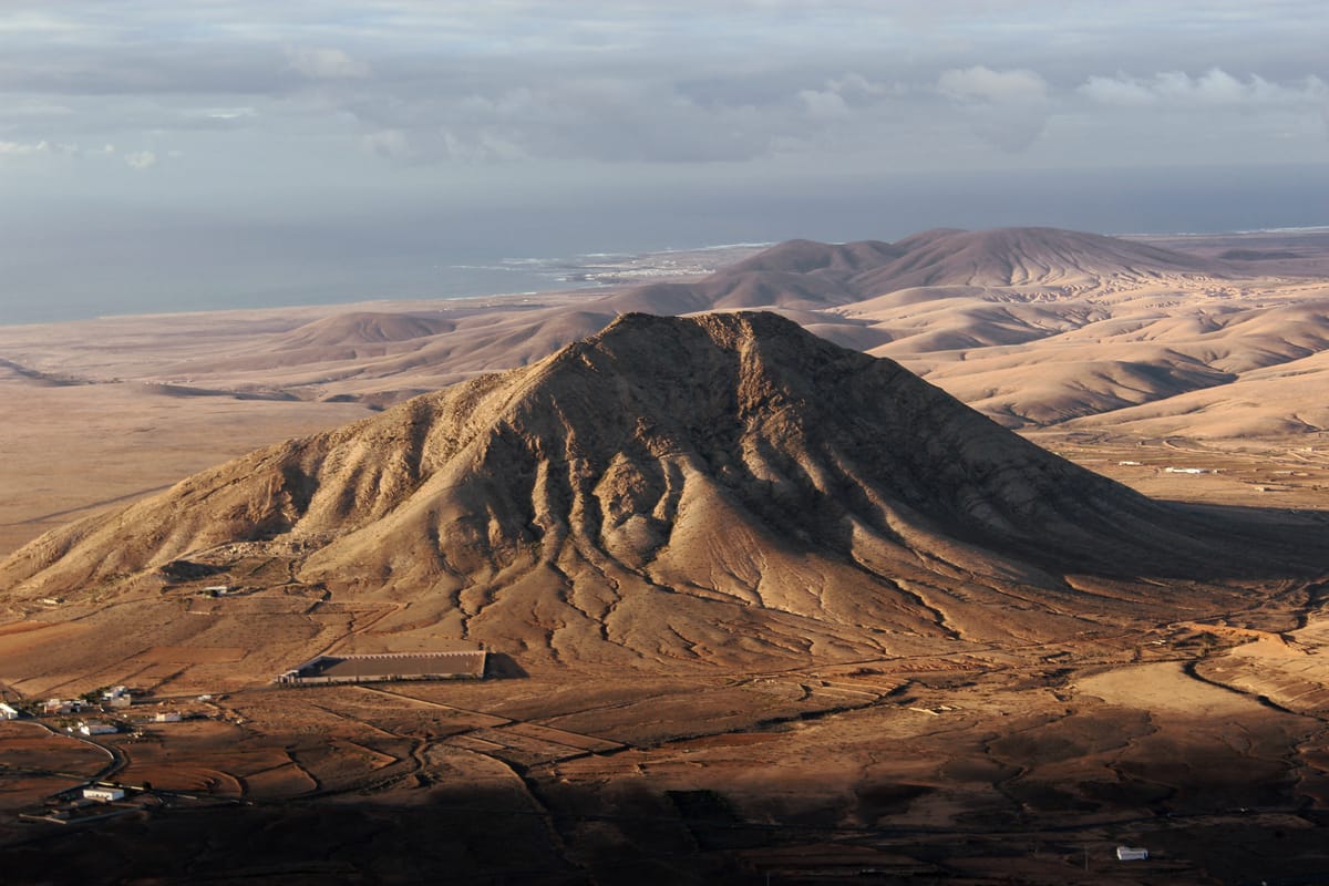 Montanha de Tindaya vista à distância, em planície árida de Fuerteventura