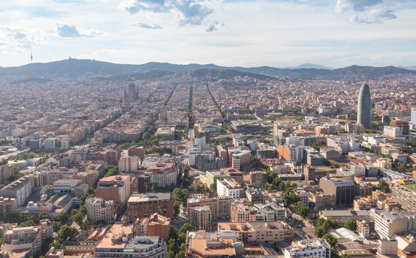 Vista aérea da malha quadriculada do Eixample, em Barcelona, com a serra de Collserola ao fundo