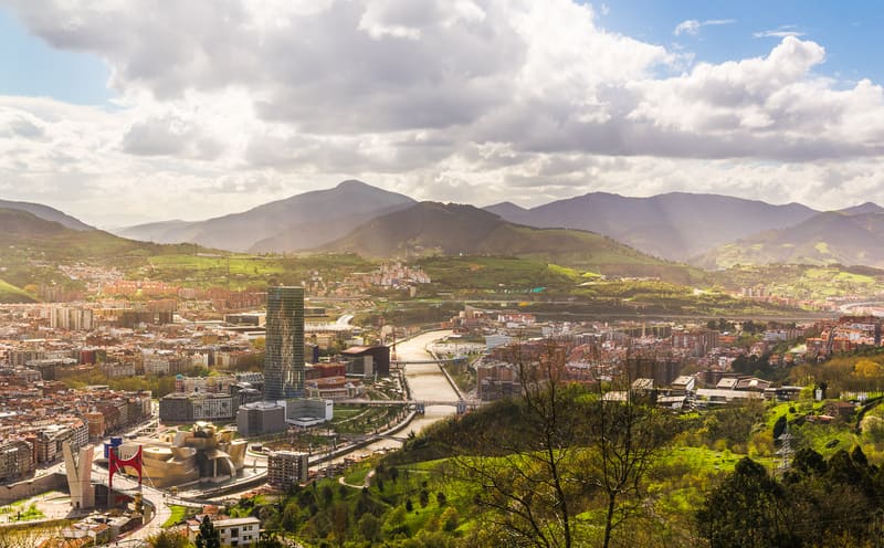 Vista do Museu Guggenheim Bilbao com fachada de titânio à beira da ria do Nervión, ao entardecer