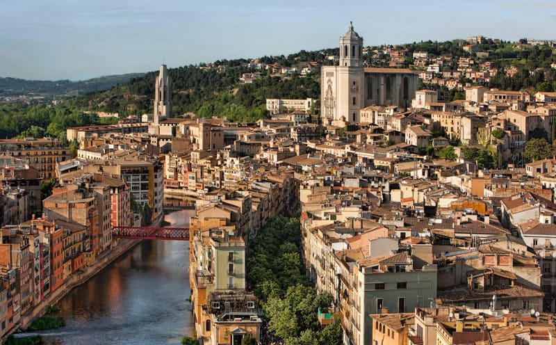 Fachadas coloridas das casas debruçadas sobre o rio Onyar em Girona, com a catedral gótica ao fundo