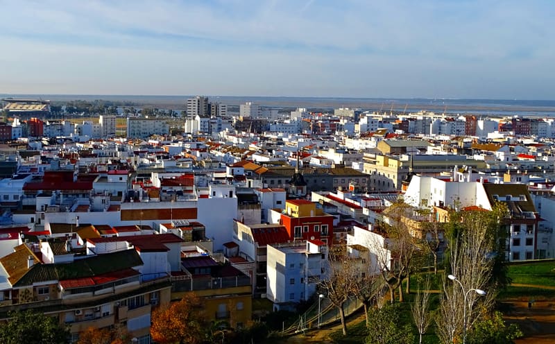 Vista do rio Odiel em Huelva ao entardecer, com o antigo cais de ferro de Riotinto e os edifícios do porto ao fundo