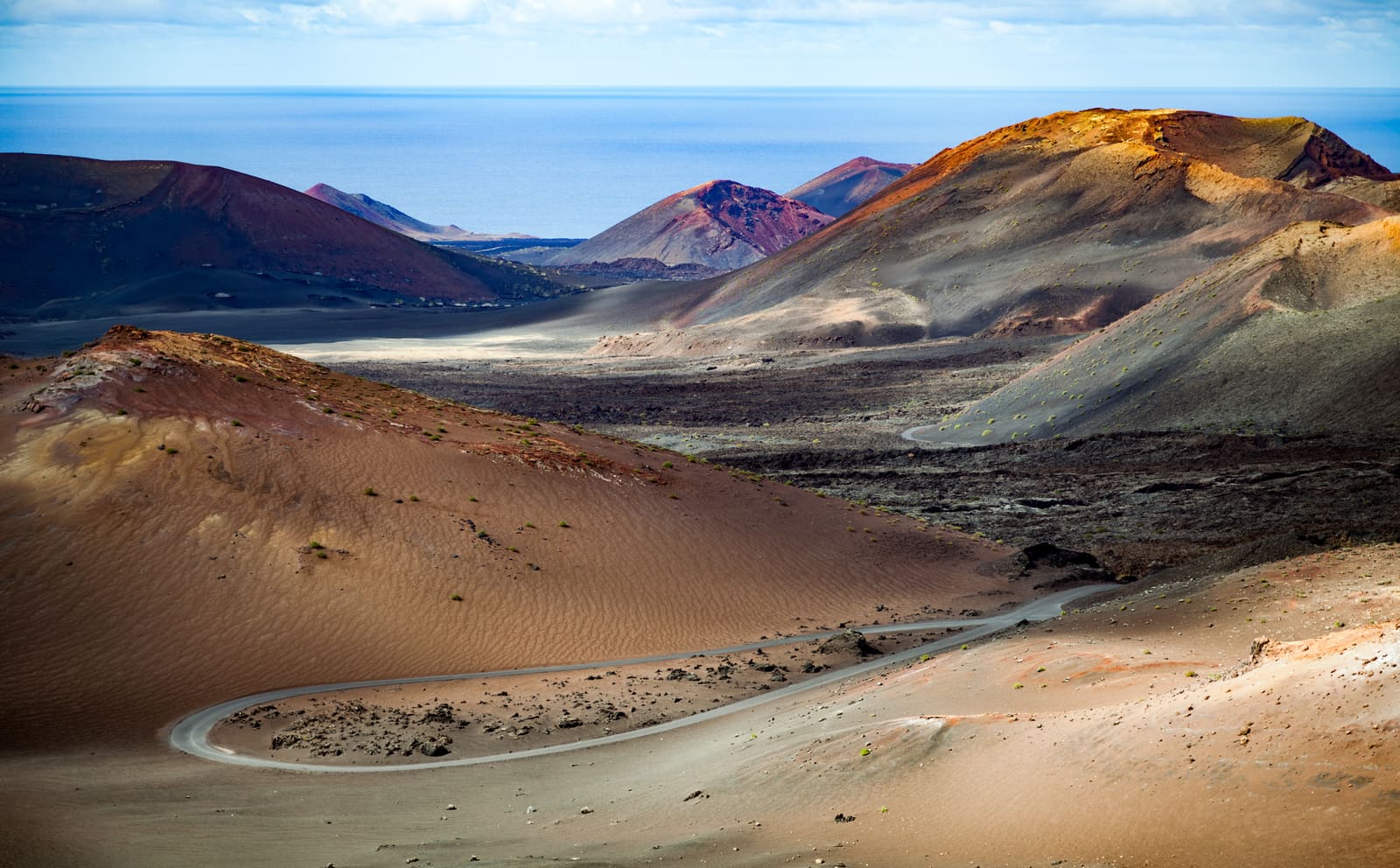 Cones vulcânicos avermelhados e estrada sinuosa no Parque Nacional de Timanfaya, em Lanzarote