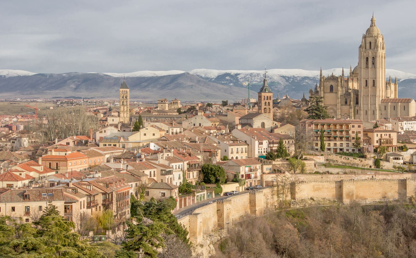 Aqueduto romano de Segovia ao entardecer, com os seus arcos de granito dourado erguendo-se sobre a Plaza del Azoguejo.
