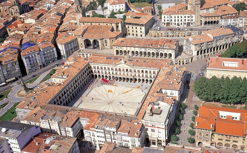 Vista aérea do casco medieval em forma de amêndoa de Vitoria-Gasteiz, com a Catedral de Santa María a dominar o horizonte e os telhados da cidade basca ao entardecer